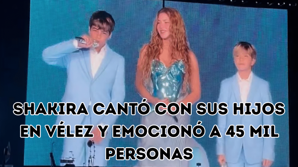 Shakira sonriendo en el escenario acompañada por sus hijos Milan y Sasha, quienes visten trajes celestes y sostienen micrófonos.